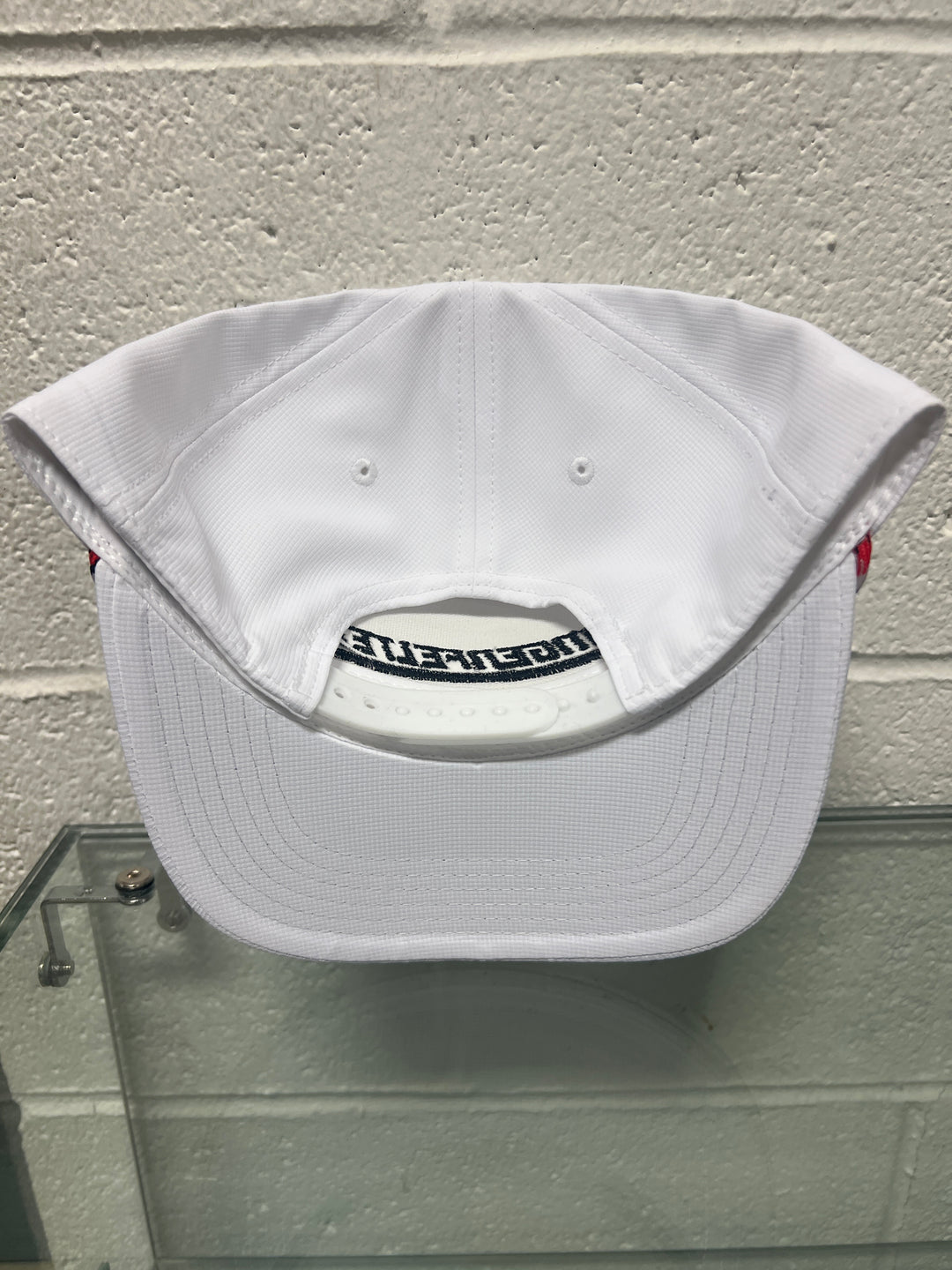 White cap with a brand logo on a textured wall