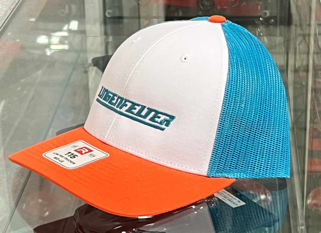 A trucker-style baseball cap with a white front panel, light blue mesh back panels, and an orange visor. The front panel features the brand name 'UNIDEFWEITER' in teal lettering with a white outline.