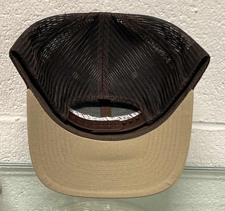 A trucker-style baseball cap viewed from the back, featuring a beige flat brim and a dark brown mesh back. The brand name 'Grunt Style' is embossed on the brown leather underband.