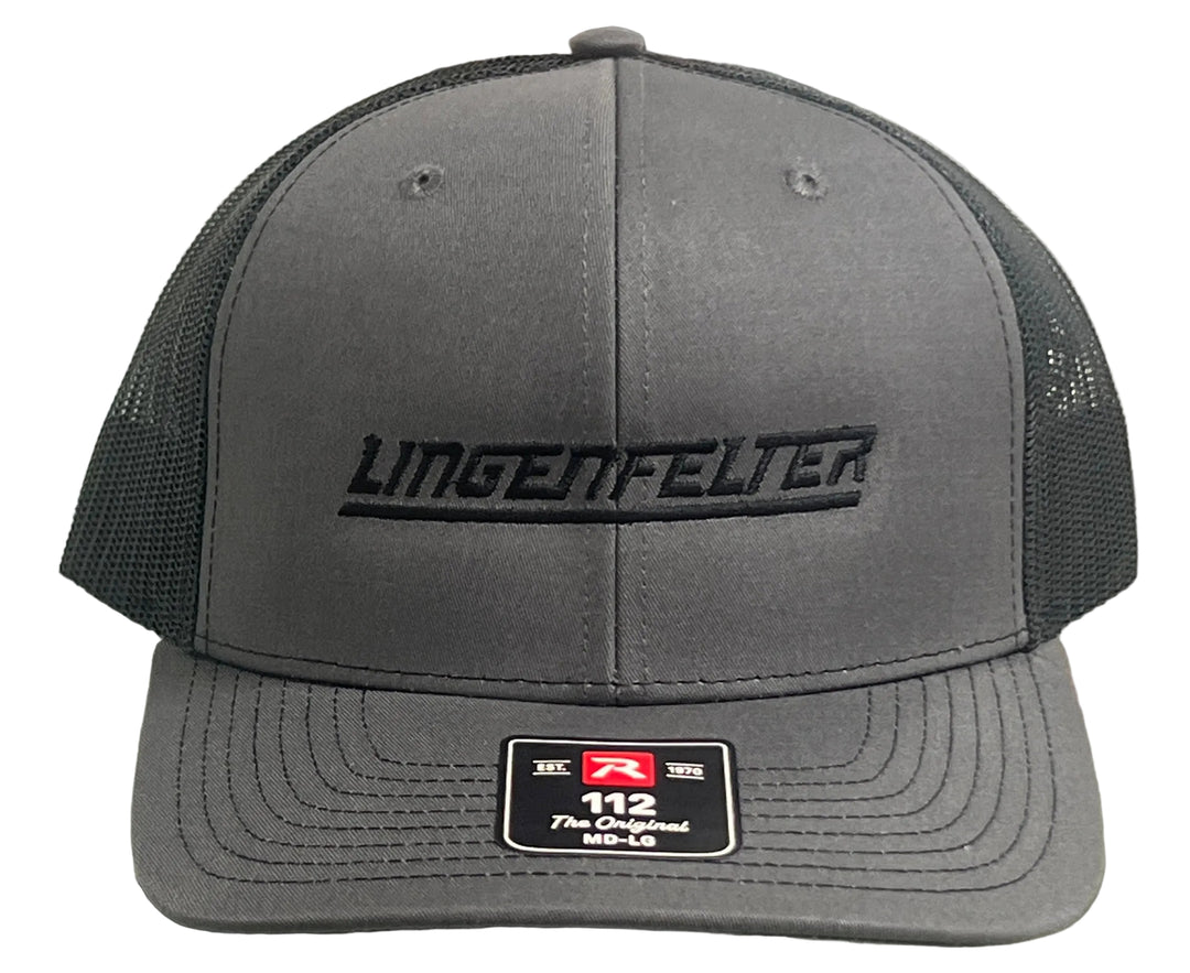 A dark gray trucker hat with black mesh back panels and black embroidered 'LINGENFELTER' branding on the front. A size patch for size 112 is visible on the brim.