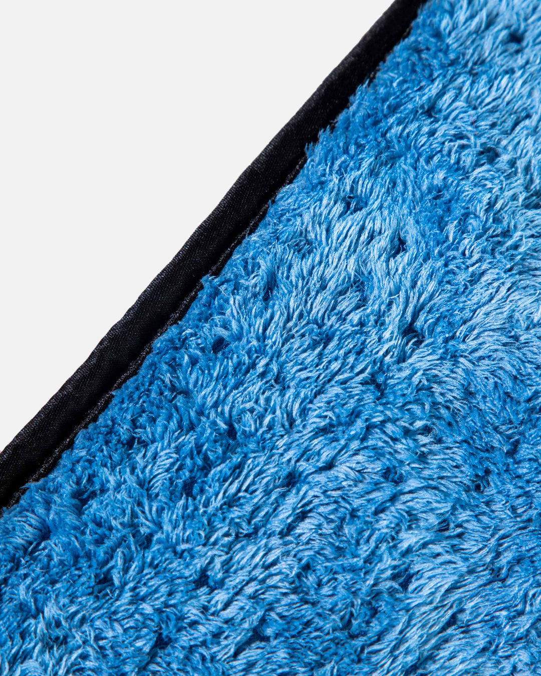 Close-up of a blue textured rug corner with a white background