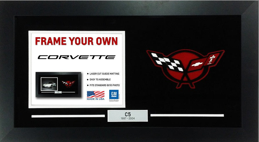 A black Corvette C5 framed slide-in photo display with a black background, a white insert card reading 'FRAME YOUR OWN CORVETTE,' a red Corvette wing-and-cross logo on the right, and a small label at the bottom that says 'C5 1967-2014.'.