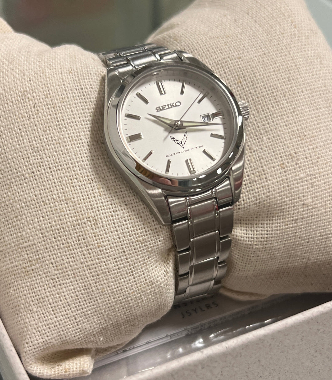Silver watch with a white face on a beige cushion in a box