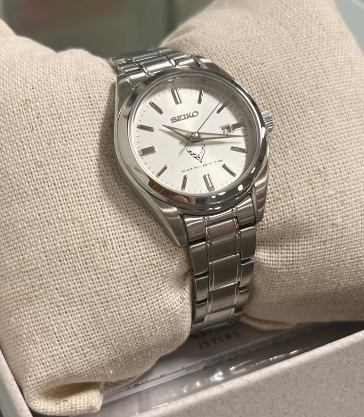 Silver watch with a white face on a beige cushion in a box