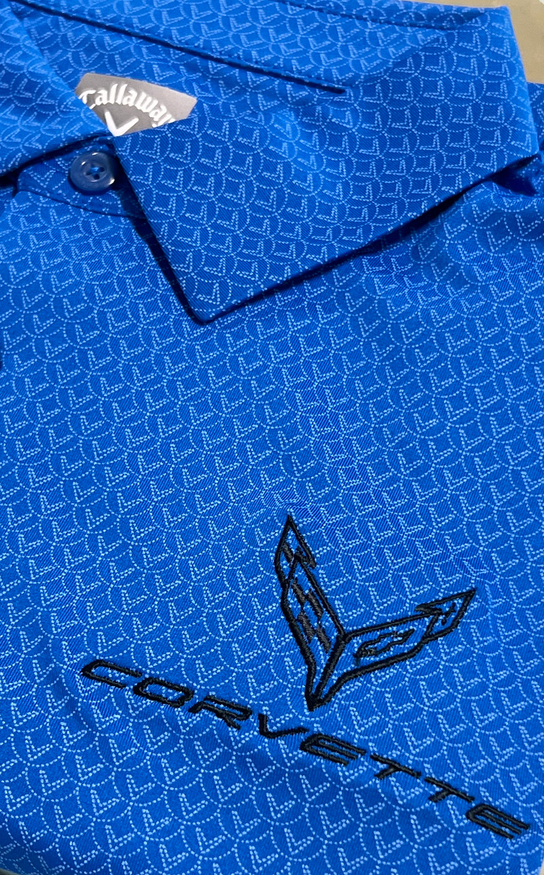 Close-up of a blue Callaway golf shirt with a repeating geometric pattern and a black embroidered Corvette logo on the front.