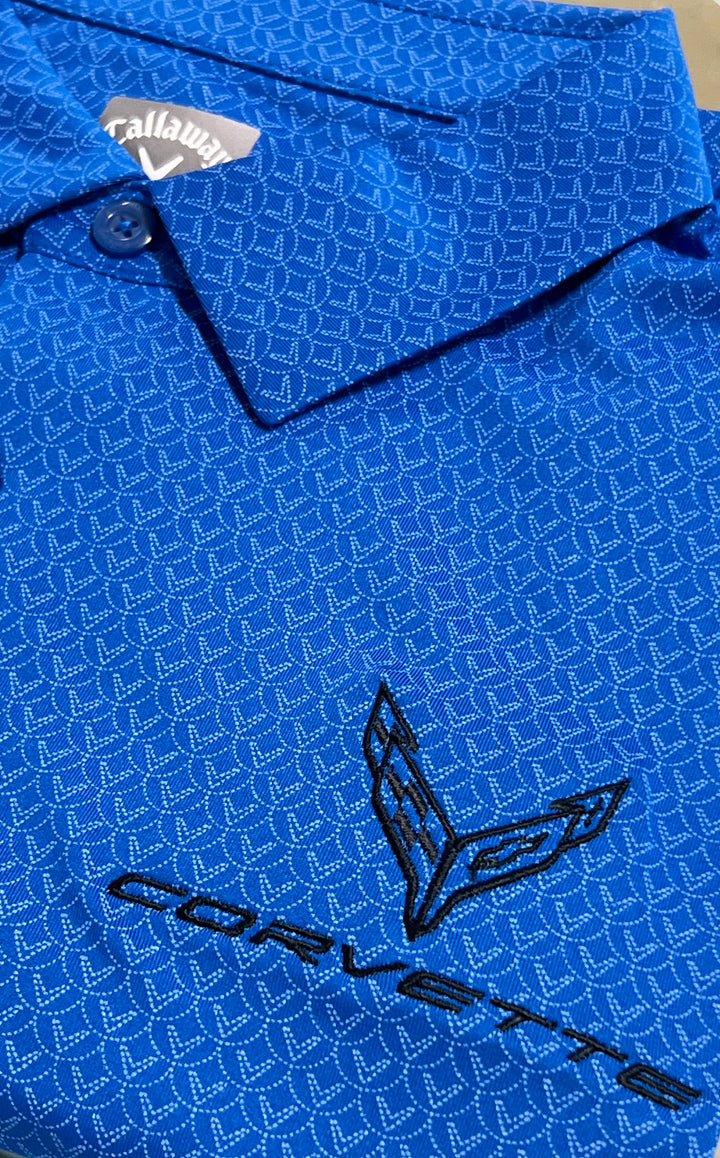 Close-up of a blue Callaway golf shirt with a repeating geometric pattern and a black embroidered Corvette logo on the front.