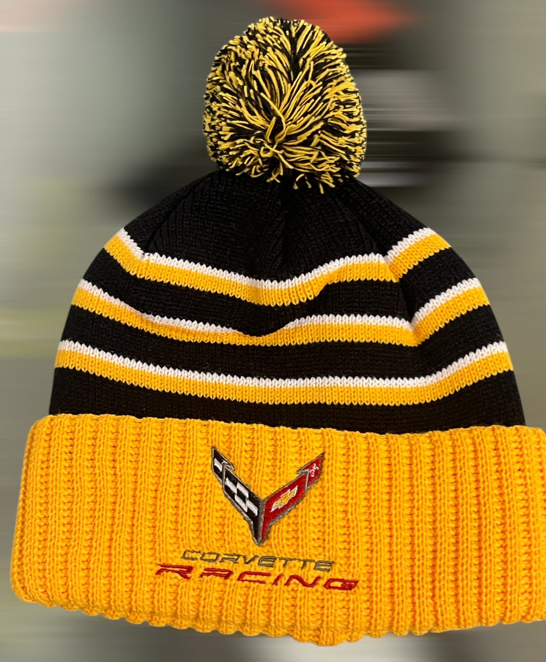 Yellow knit C8 Corvette Racing beanie hat with pom-pom, made by Lingenfelter Race Gear, featuring racing graphics.