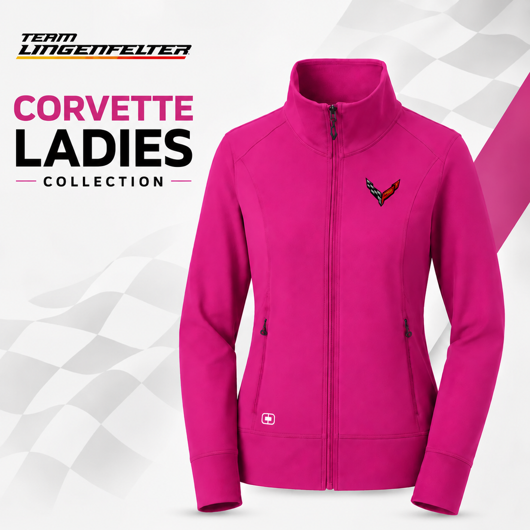 A bright pink zip-up jacket for women, featuring a small Corvette logo on the left chest and a small white cross on the lower right front hem. The jacket is displayed on a white and gray checkered background with 'Team Lingenfelter' and 'Corvette Ladies Collection' text on the left.