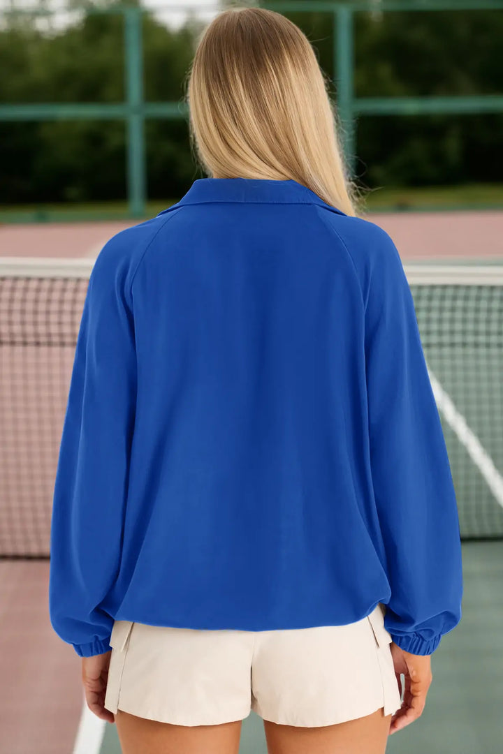 Person wearing a blue jacket on a tennis court