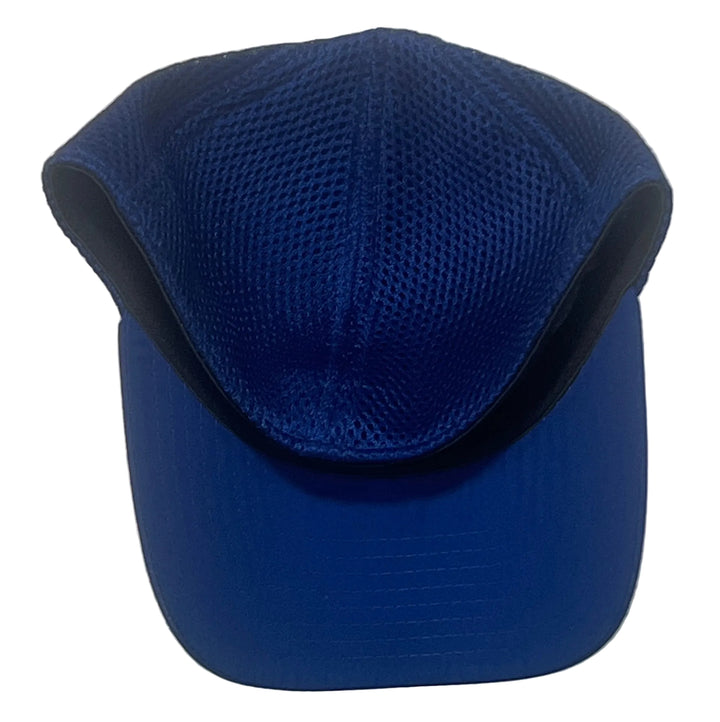 A royal blue baseball cap with a mesh crown and solid curved brim, photographed against a white textured wall.
