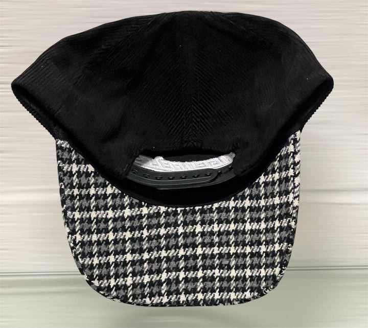 Black cap with a patterned brim on a light wooden surface