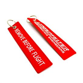 Team Lingenfelter Remove Before Flight keychain with red fabric tag and metal keyring, featuring bold black lettering.